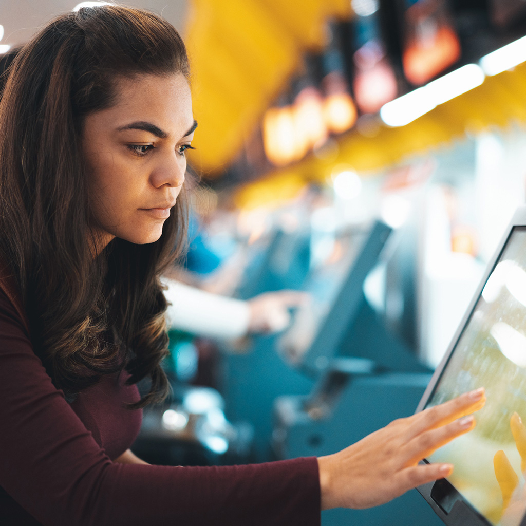 Visitor health insurance plan for Dubai & UAE. Government Compliant Travel health coverage. Woman at airport at self check-in kiosk.